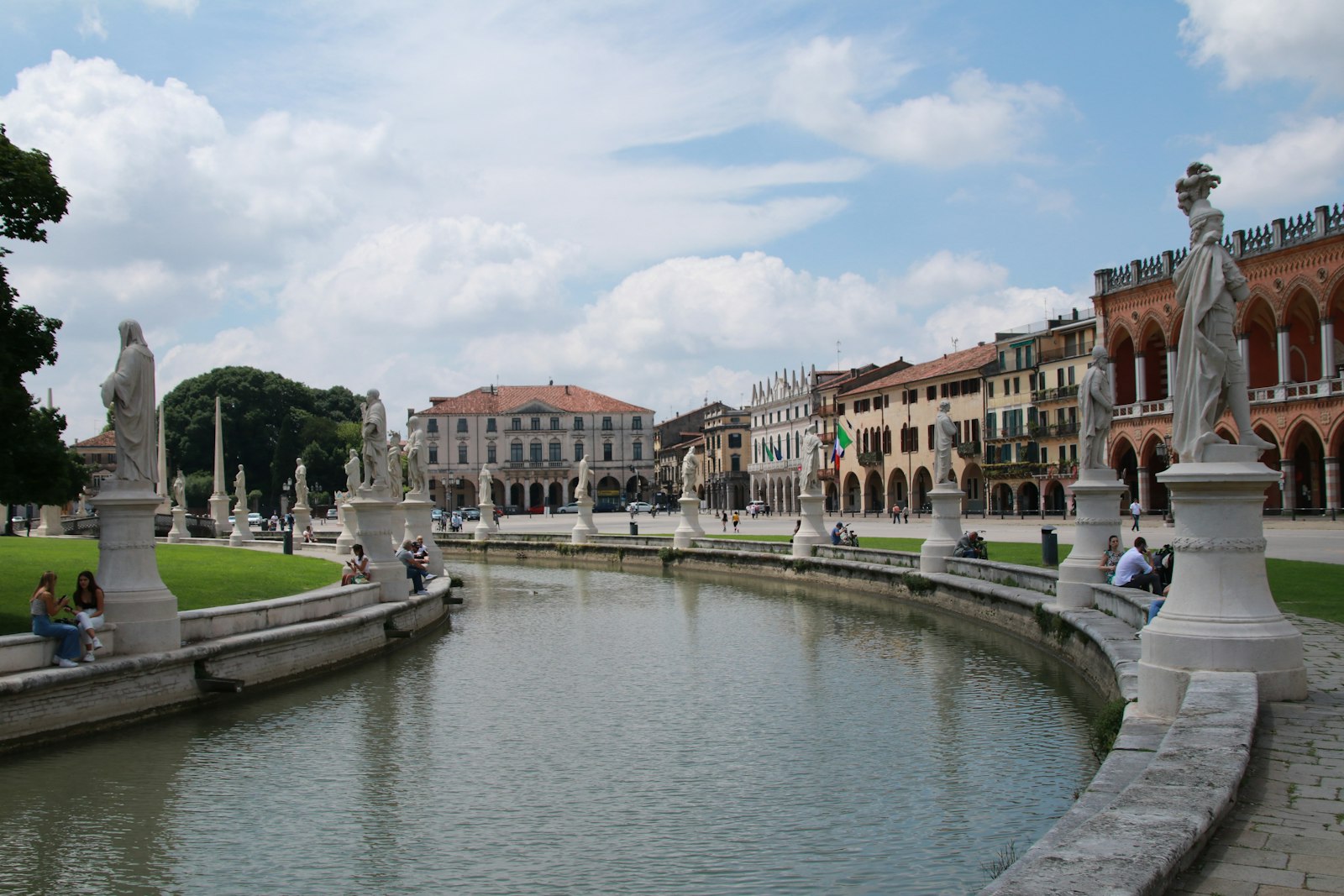Prato della Valle a Padova: il canale con le statue e alcune persone sedute sulle panchine
